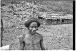 Adolescent boy next to a house, fences in background