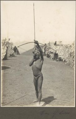 Man of Evese [pointing a bow and arrow at the sky, with village in background]