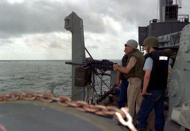 Crew members of the of the submarine tender USS HOLLAND (AS-32) take part in a live fire qualification drill with the Mark 19 belt-feed 40mm grenade launching machine gun while at sea between Guam and Sasebo, Japan