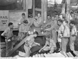 MEMBERS OF NO. 24 (VENGEANCE) SQUADRON RAAF HAVING A CUP OF TEA AND CAKE. SHOWN: FLYING OFFICER (FO) G. L. STEVENSON, NEWCASTLE, NSW; FO F. WALSH, ARTARMON, NSW; FLIGHT SERGEANT (FLT SGT) O. SHAW, ..