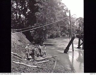 DONADABU, NEW GUINEA. 1943-11-03. SAPPERS OF THE 24TH AUSTRALIAN FIELD COMPANY, ROYAL AUSTRALIAN ENGINEERS CONSTRUCTING A NEW EIGHT SPAN WOODEN BRIDGE OVER THE LALOKI RIVER. SHOWN: QX18824 SAPPER ..