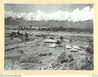 LAE, NEW GUINEA, 1944-03-27. ONE OF A SERIES OF PHOTOGRAPHS VIEWING THE WHARVES, SHIPPING, NEW ROADS, BUILDINGS AND THE AIRSTRIP WITH SALAMAUA POINT IN THE BACKGROUND. (JOINS WITH PHOTOGRAPHS ..