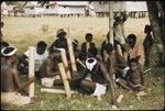 Musicians; one with a guitar, and others with lengths of bamboo to pound on ground