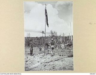 MALAGUNA MISSION, NEW BRITAIN. 1945-09-10. TROOPS OF 4 INFANTRY BRIGADE HOISTING THE AUSTRALIAN FLAG ON THE BEACH, SOON AFTER LANDING, WHILE BRIGADIER C.R.V. EDGAR (LEFT) LOOKS ON