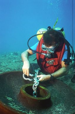 Utilityman Third Class (UT3) Gilbert Negrette, a member of Underwater Construction Team Two (UCT-2), places a shackle on a mooring anchor during cable system repairs at the Pacific Missile Range Facility off Kauai, Hawaii