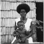 Woman and infant in front of house