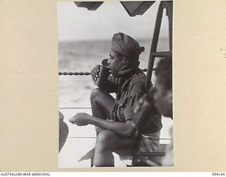 TINIAN, BOUGAINVILLE. 1945-07-18. PRIVATE J. PATTIPEILOHY, NETHERLANDS EAST INDIES ARMY, DRINKING TOMATO JUICE ON THE DECK OF THE MOTOR LAUNCH ML1327. THE VESSEL IS BEING USED BY THE ALLIED ..