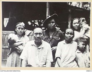 BITAPAKA, NEW GUINEA. 1945-11-04. PRIVATE SHUI HONG, NOW OF 118 GENERAL HOSPITAL, WHO SERVED WITH THE NEW GUINEA VOLUNTEER RIFLES IN NEW GUINEA, HAS A REUNION WITH HIS FAMILY