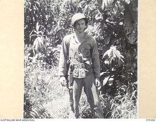 LAE, NEW GUINEA. 1944-02-18. TECHNICAL SERGEANT J. DEATON, UNITED STATES ARMY, DEMONSTRATING AN AMERICAN JUNGLE UNIFORM AND EQUIPMENT