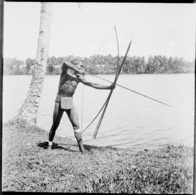 Ramu man aiming bow and arrow into river, Ramu River [?], New Guinea, 1935, 2 / Sarah Chinnery