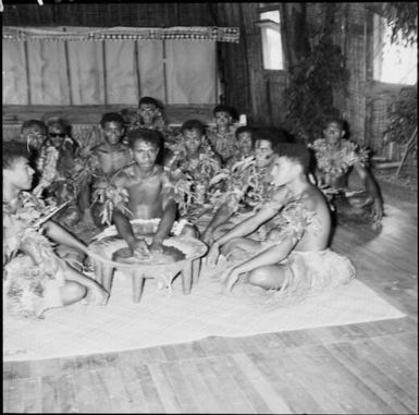 Yaqona ceremony by group of Fijian men, dressed in traditional costumes, in a grass hut, Nasalai, Fiji, 1966, 1 / Michael Terry