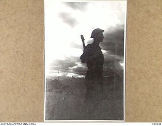 RAMU VALLEY, NEW GUINEA, 1943-10-01. AN INFANTRYMAN OF THE 2/27TH AUSTRALIAN INFANTRY BATTALION, SILHOUETTED AGAINST THE LATE AFTERNOON SUN IN THE VALLEY