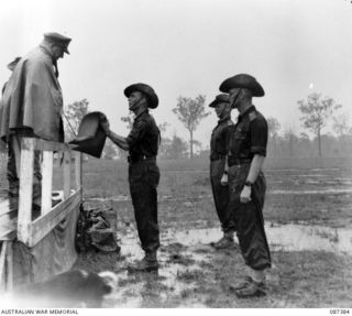 HERBERTON, QUEENSLAND. 1945-03-03. MAJOR GENERAL G.F. WOOTTEN, GENERAL OFFICER COMMANDING 9 DIVISION, (4), PRESENTS TROPHIES TO OFFICERS OF THE 24 INFANTRY BRIGADE REPRESENTING UNITS AT THE ..