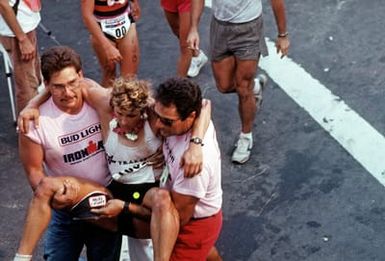 Volunteers carry an exhausted contestant from the finish line of the 26-mile marathon, part of the 1987 Ironman Competition
