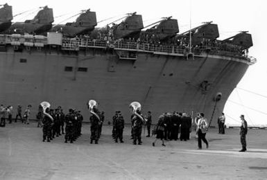 The 2nd Marine Division Band plays as the 32nd Marine Amphibious Unit returns from duty in Beirut, Lebanon. They were a part of the United Nations peacekeeping force. The ship in front of the band is the amphibious assault ship USS GUAM (LPH-9)