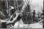 Pig festival, wig ritual, Tsembaga: man adjusts wig frame sewn onto another man's hair