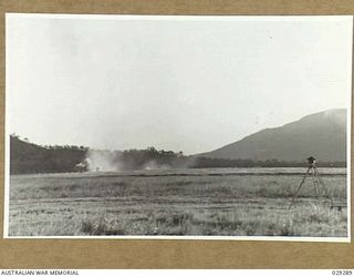 TOWNSVILLE, AUSTRALIA. 1942-11. GAS SHELL BURSTING OVER "GUINEA PIGS" DURING THE DEMONSTRATION GAS SHELL SHOOT BY 5TH FIELD REGIMENT, ROYAL AUSTRALIAN ARTILLERY. THE DUST ON THE LEFT IS CAUSED BY ..