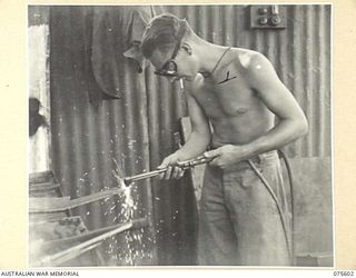 MARKHAM VALLEY, NEW GUINEA. 1944-08-28. VX81834 STAFF SERGEANT W.A. CARHEER (2), WELDER, 214TH LIGHT AID DETACHMENT, ATTACHED TO THE 4TH FIELD REGIMENT, USING AN OXY-ACETYLENE TORCH TO CUT STEEL ..