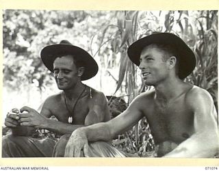 FINISTERRE RANGES, NEW GUINEA. 1944-03-15. NX67491 SAPPER W. ABBOTT ( ) AND NX28487 CORPORAL J.D. LAW ( ), MEMBERS OF NO. 2 PLATOON, 2/4TH FIELD COMPANY, PAUSE FOR A CIGARETTE AND REST IN THE SHADE