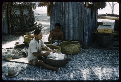 John Simona Marsters, front, and Tio Marsters, grating arrowroot into wooden troughs, on Palmerston Island, Cook Islands