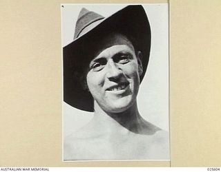 PORT MORESBY, PAPUA. 1942-07. AN AUSTRALIAN SOLDIER IN NEW GUINEA STOPS WORK FOR A MOMENT TO SMILE FOR THE PHOTOGRAPHER