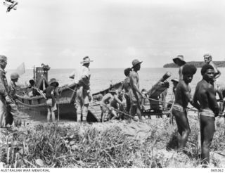 BIAMU, ORO BAY, NEW GUINEA. 1942-11-11. GUNNERS OF THE 2/5TH FIELD REGIMENT, ASSISTED BY LOCAL NATIVES, DRAGGING ONE OF THEIR GUNS OFF CAPTURED JAPANESE BARGE AT BIAMU