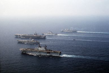 Ships from four nations sail in formation during the NATO Southern Region exercise DRAGON HAMMER '90. The ships are, from front: amphibious assault ship USS SAIPAN (LHA 2), the Spanish aircraft carrier SPS PRINCIPE DE ASTURIAS (R-11), the nuclear-powered aircraft carrier USS DWIGHT D. EISENHOWER (CVN 69), the Italian light aircraft carrier ITS GIUSEPPE GARIBALDI (C-551), and the British light aircraft carrier HMS INVINCIBLE (R-05)