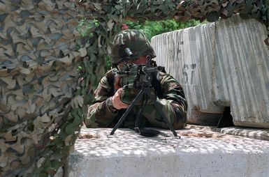 Private (PVT) Brian Horn, US Army (USA), A/Company, 1ST Battalion, 17th Infantry Division mans his 5.56mm M249 Squad Automatic Weapon while guarding a security checkpoint at Orote Point, Guam during Exercise TANDEM THRUST '99