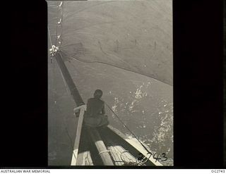 PORT MORESBY, PAPUA. C. 1944. A CREW MEMBER ON THE BOW OF A SAILING VESSEL USED BY THE RAAF RESCUE SERVICE