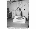 J. A. Zadik displaying unusual fish caught in a contest aboard the USS CHILTON, 1947