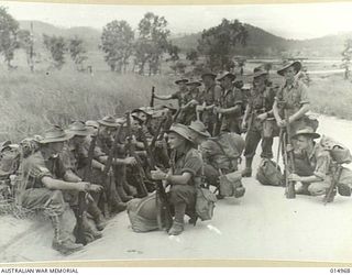 1943-06-09. NEW GUINEA. AUSTRALIANS TAKE A REST ON THE SIDE OF A DUSTY NEW GUINEA ROAD. THE PATROL RESTS AFTER MARCHING MANY MILES WITH FULL PACK. (NEGATIVE BY N. BROWN)