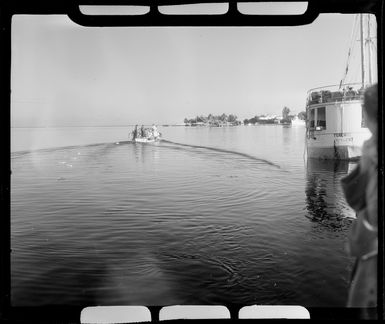 Small passenger boat departs Tahiti heading towards TEAL (Tasman Empire Airways Limited) flying boat; part of the boat Terehau can be seen