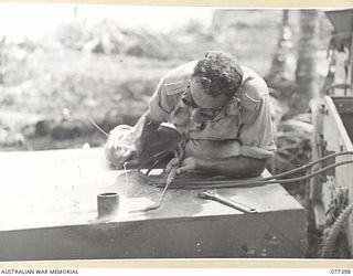 PALMALMAL PLANTATION, NEW BRITAIN. 1944-11-29. SAPPER J. MCCABE, 17TH FIELD COMPANY, 48TH DEPUTY COMMANDER ROYAL ENGINEERS (WORKS) WELDING A 2" UNION INTO A 400 GALLON STEEL TANK