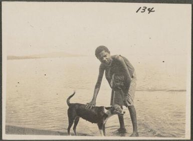 Tolai boy on a beach with a dog, New Britain Island, Papua New Guinea, probably 1916