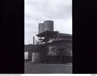 RABAUL, NEW BRITAIN, 1946-03-29. WATER STORAGE TANKS AT THE AUSTRALIAN ARMY CANTEENS SERVICE CORDIAL FACTORY. THE WATER IS PUMPED FROM A WELL AT THE RATE OF 6,000 GALLONS DAILY, FILTERED AND STORED ..