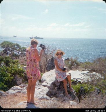 Two women overlooking the coast - one video recording the other