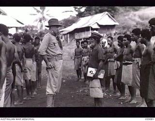 NX155085 Captain R. G. Ormsby (centre left) Australian and New Guinea Administration Unit, checking over native recruits with Dahu (centre right) the paramount chief of the Bukaua (Bukawa) tribe. ..