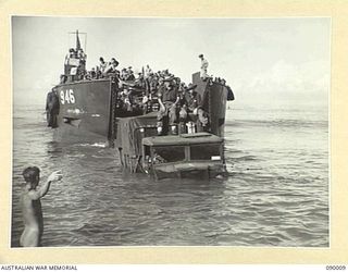 TOKO, BOUGAINVILLE. 1945-03-28. B SQUADRON, 2/4 ARMOURED REGIMENT TROOPS AVOIDED GETTING WET BY RIDING ASHORE ON THE ROOF OF A 3 TON TRUCK TOWED OFF AN AMERICAN OPERATED LANDING CRAFT TANK BY A ..