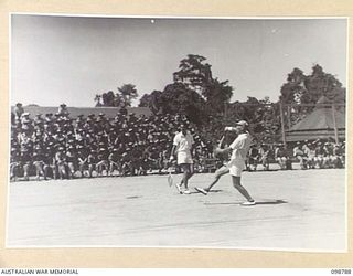 TOROKINA, BOUGAINVILLE. 1945-11-17. MR B.G. TONKIN, YMCA REPRESENTATIVE, 8 INFANTRY BATTALION AND A FORMER VICTORIAN INTERSTATE PLAYER, SMASHING A BALL BACK IN THE DOUBLES MATCH DURING AN ..