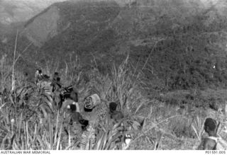 MARKHAM VALLEY AREA? NEW GUINEA. C.1945. IN THE FIELD WHILE ON PATROL, NATIVE POLICE AND BEARERS WITH EQUIPMENT, INCLUDING A BATTERY, FOR THE MOBILE PROPAGANDA UNIT, FAR EASTERN LIAISON OFFICE