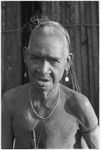 An elderly Kwaio woman, her woven 'purse' over her head, wearing shell earrings