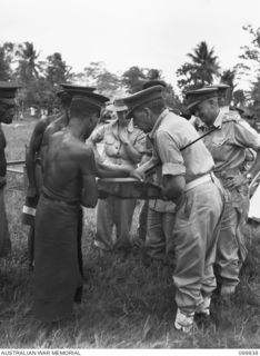 LAE, NEW GUINEA, 1946-02-14. AT A SPECIAL PARADE, MAJOR GENERAL B.M. MORRIS,GENERAL OFFICER COMMANDING AUSTRALIAN NEW GUINEA ADMINISTRATIVE UNIT, PRESENTED GIFTS (FRAMED COLOURED PHOTOGRAPHS OF ..