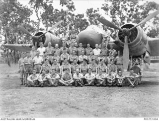 Group portrait of air and ground crew of B Flight, No. 30 Squadron RAAF, on and in front of one of the squadron’s Beaufighter aircraft at Ward’s Strip. Back row, left to right (seated on the ..