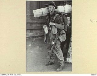 CAIRNS, QLD. 1944-10-30. PRIVATE ROSS, A COMPANY, 2/4 INFANTRY BATTALION, LADEN WITH TROPICAL GEAR, ON THE WHARF DURING EMBARKATION FOR NEW GUINEA ABOARD THE TROOPSHIP USS MEXICO