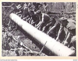 BOUGAINVILLE. 1945-05-21. PIONEERS OF 24 INFANTRY BATTALION, ASSISTED BY ENGINEERS, LAYING AN ARMCO CULVERT IN THE CREEK SOUTH OF EGAN'S RIDGE TO ALLOW SUPPLIES ALONG THE BUIN ROAD TO FORWARD ..