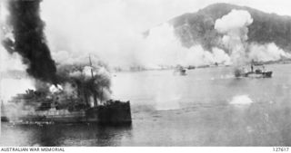 SIMPSON HARBOUR, NEW GUINEA. 1943-11-02. SMOKE RISES INTO THE AIR AFTER A DIRECT HIT IS SCORED ON A JAPANESE TROOPSHIP AND CARGO VESSEL TIED TOGETHER. ANOTHER STRING OF RAAF BOMBS CAN BE SEEN ..