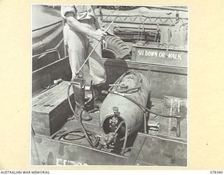 TOROKINA, BOUGAINVILLE ISLAND. 1945-01-17. A MEMBER OF THE 19TH MALARIAL CONTROL UNIT DEMONSTRATING A MODEL "L" SPRAY GUN AND A PRESSURE TANK USED ON A 15 CWT 4 X 4 VEHICLE WHEN SPRAYING CREEKS AND ..