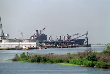 The Military Sealift Command oiler USNS BENJAMIN ISHERWOOD (T-AO 191) is docked at a pier.
