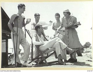 NEW GUINEA. 17 NOVEMBER 1943. MEMBER OF THE AUSTRALIAN ARMY MEDICAL WOMEN'S SERVICE (AAMWS) ON SERVICE AT AN AUSTRALIAN FIELD HOSPITAL. SERGEANT H. BEALE POURS A DRINK FOR PRIVATE (PTE) W.H. GOUGH ..