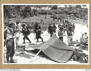 KANOMI BEACH, NEW GUINEA. 1944-01-05. TROOPS OF THE 2/23RD AUSTRALIAN INFANTRY BATTALION, 26TH AUSTRALIAN INFANTRY BRIGADE, 9TH AUSTRALIAN DIVISION WAITING TO BOARD BARGES FOR THEIR JOURNEY UP THE ..